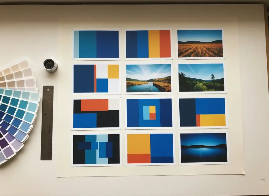 Printed postcard proofs laid out in a grid beside a swatch fan, loupe and steel ruler